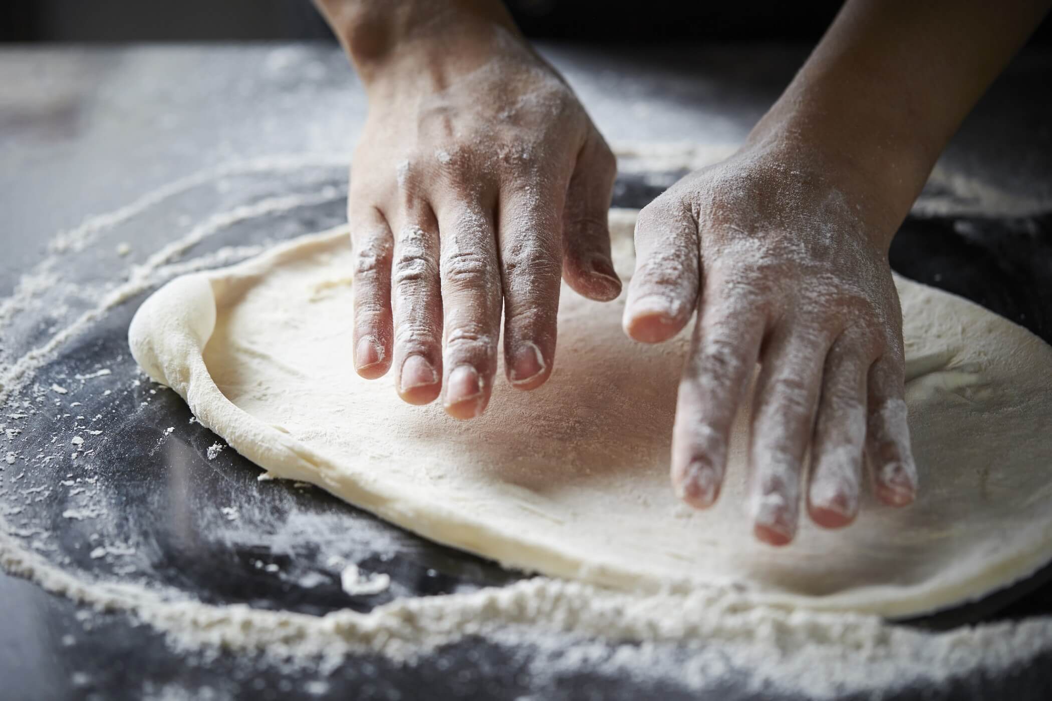 hand shaping dough into a pizza